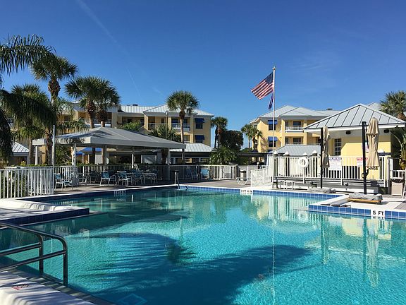 Community heated pool and deck area with chaise lounges, umbrellas chairs and tables, tiki bar, firepit, barbeques, separate men's and women's bathrooms