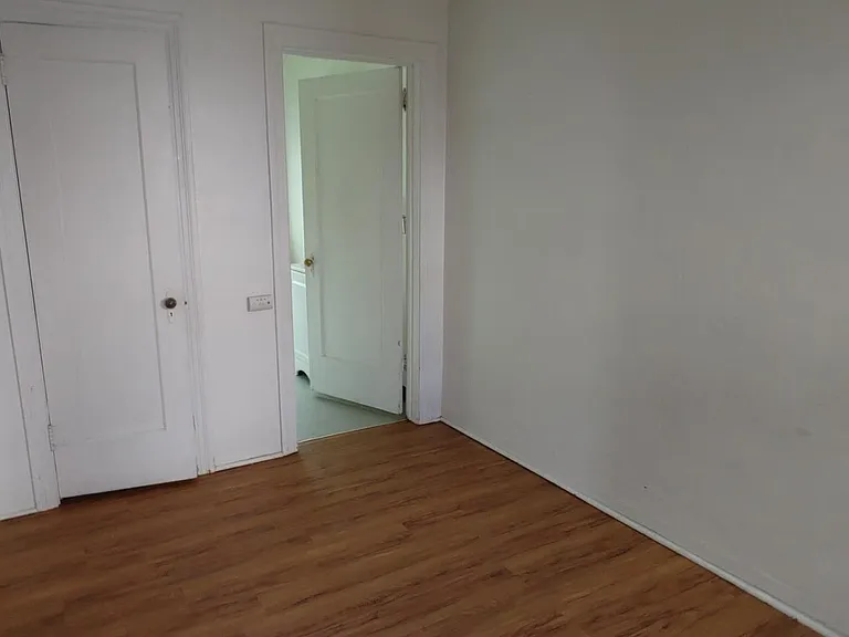 The view from the bedroom into the bedroom. The door to the left is a small walk-in closet with hanging space and some shelving.
