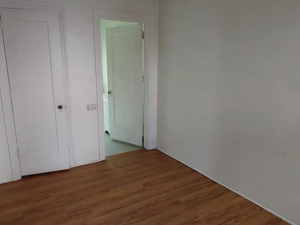 The view from the bedroom into the bedroom. The door to the left is a small walk-in closet with hanging space and some shelving.