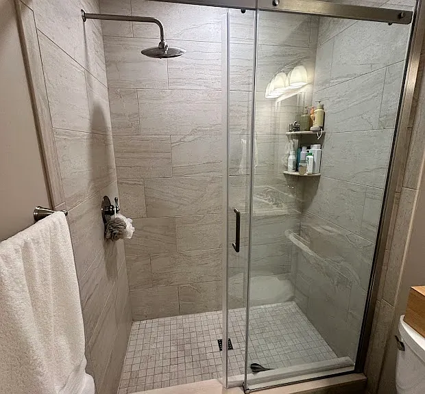 Large custom tile shower, with relaxing rain showerhead and sliding glass door.