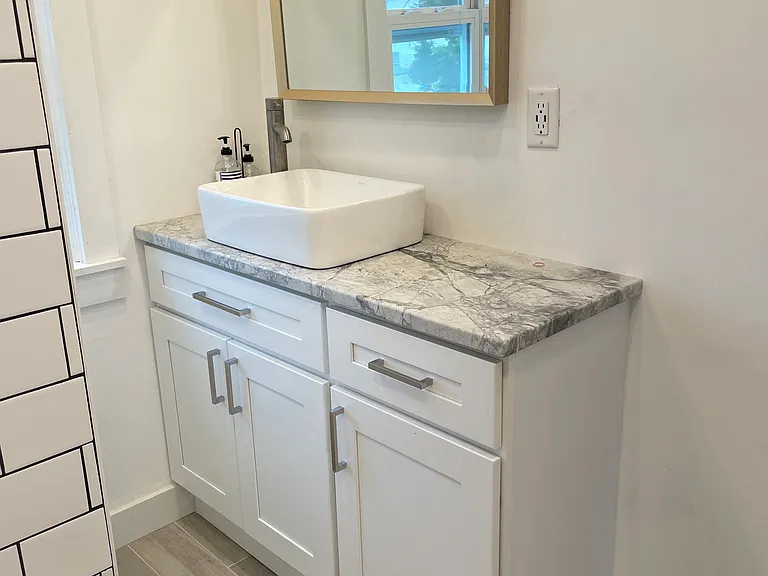 Spacious vanity area with cabinet storage, modern fixtures, vessel sink, and durable finishes that give the bathroom a fresh, updated feel.