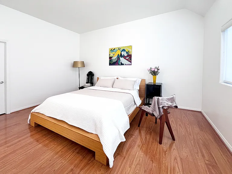 Spacious master bedroom suite featuring a clean minimalist design, high ceilings, and a modern skylight that floods the room with natural light.