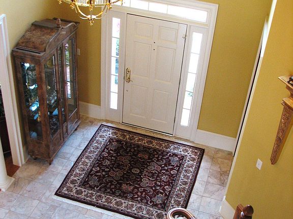 Soaring two-story foyer with decorative ledge and marble flooring. 