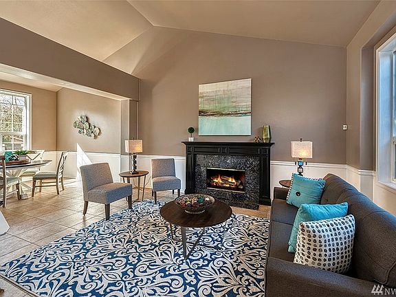 The Formal Living Room Features A Gas Fireplace, Newer Tile Floors, And Large Windows That Allow For An Abundance Of Natural Sunlight.