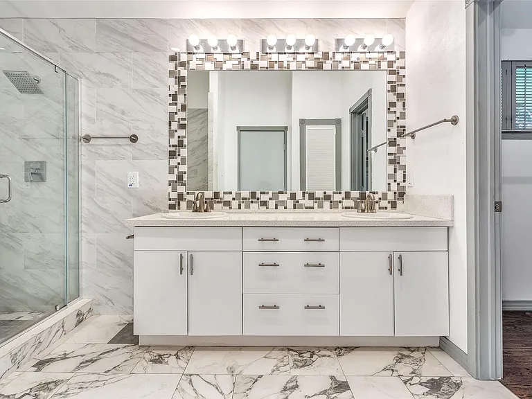 Full bathroom featuring a dual vanity with white cabinetry, light-toned countertops, and brushed nickel hardware