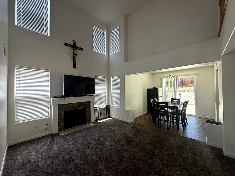 Open living area with soaring ceilings, abundant natural light, and a cozy fireplace.