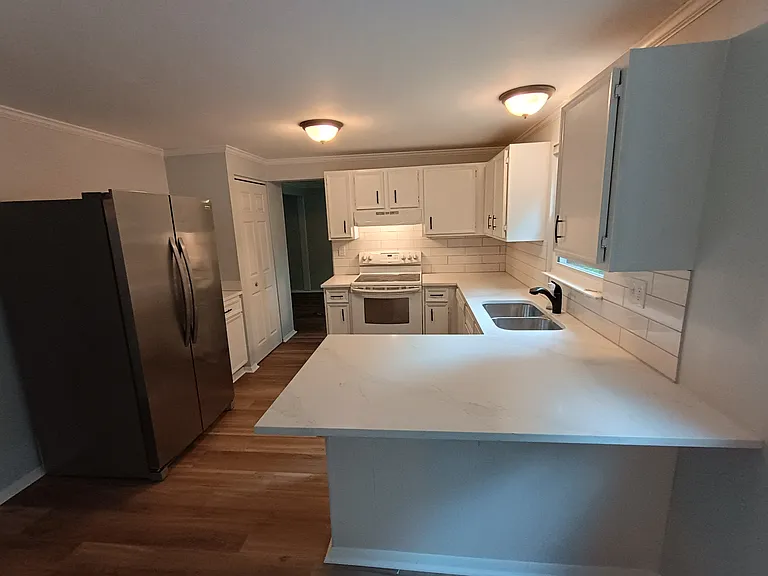 Kitchen with brand new countertops, sink, tile backsplash, and refrigerator.