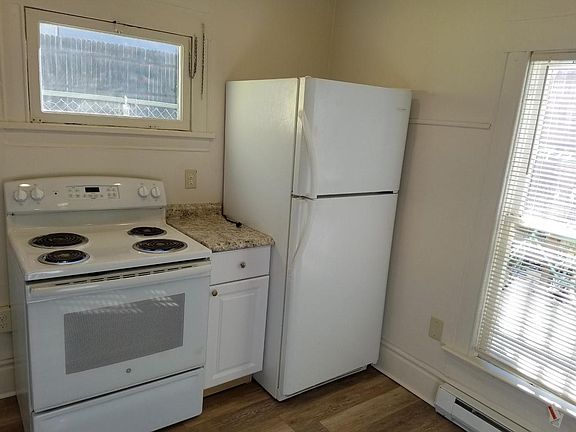 Kitchen stove, refrigerator two windows, and new flooring with baseboard heater.
