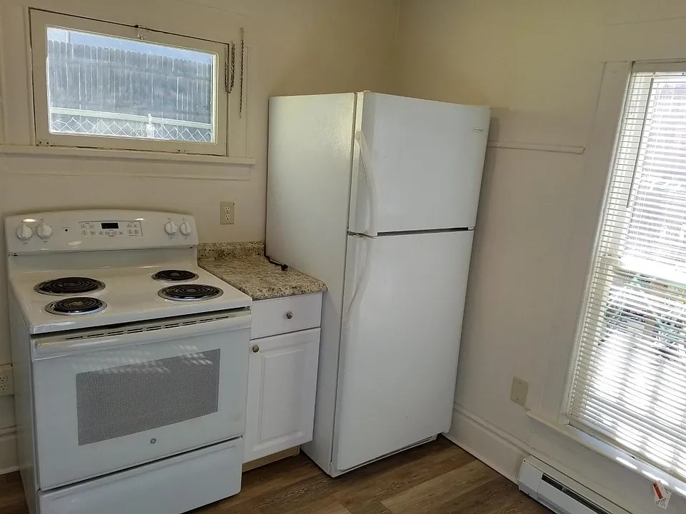 Kitchen stove, refrigerator two windows, and new flooring with baseboard heater.
