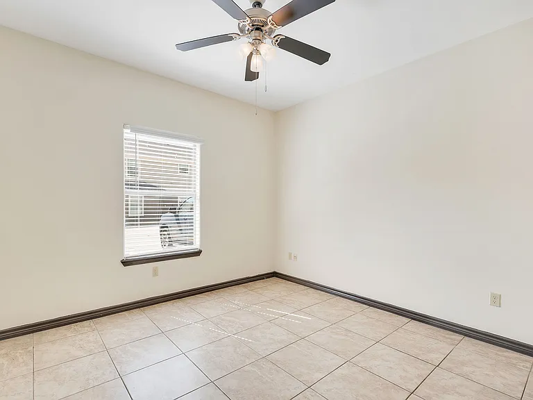 A vacant room with tile flooring and a ceiling fan, representing the interior of La Joya Apartments in Laredo, Texas