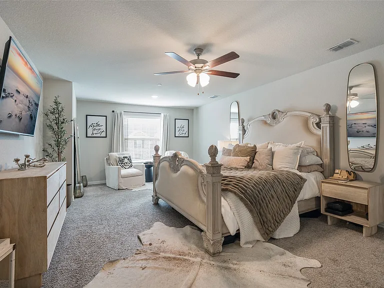 Spacious room featuring neutral carpeting, a ceiling fan, a window with curtains, and light-toned walls