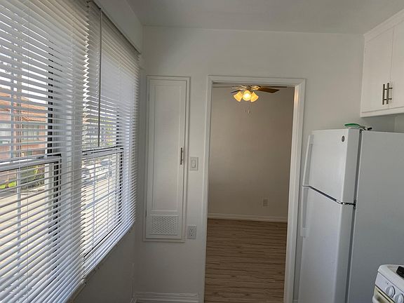 View from the kitchen with a new refrigerator and showing the large windows allowing in plenty of light looking towards the dining area.