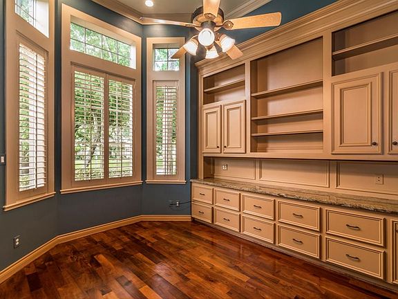 Private study is located near the entry. Wall of builtins, plantation shutters, wood flooring.