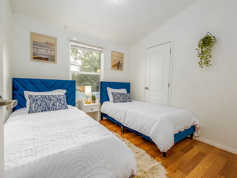 Charming second bedroom featuring two cozy single beds ideal for friends or family members traveling together. Unwind in a bright, airy environment that offers both comfort and privacy _ the perfect place to recharge after a day of adventures