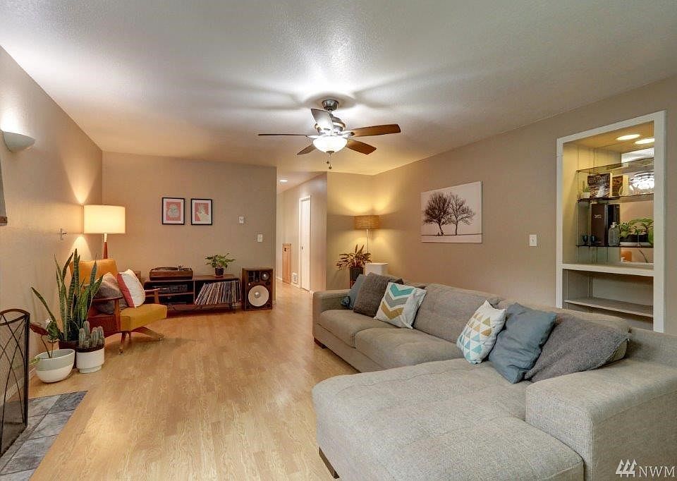 Extra large living room with wood burning fireplace, ceiling fan with light and built in shelving with recessed light.