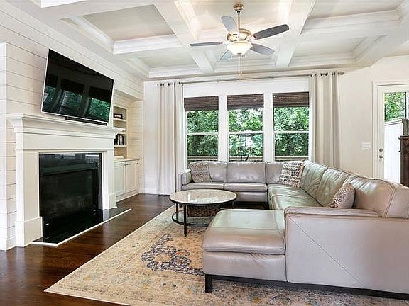 Living room with coffered ceilings; gas fireplace; shiplap-accented wall and built-in bookcase and storage. Electric blinds; complete privacy with green forest behind the entire unit!