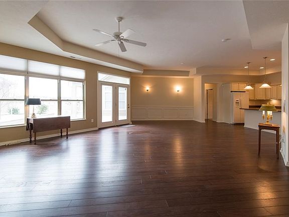 Standing at the entry area viewing the spacious and open great room with trey ceiling  and kitchen to the right. Beautiful hardwood laminate floor covering and atrium door to your private courtyard for entertaining.