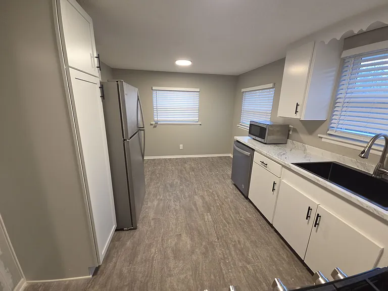 Bright kitchen with updated countertops, white cabinetry, stainless refrigerator and range, and dishwasher.