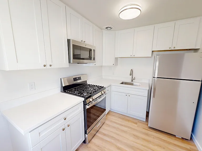 Modern kitchen with sleek stainless steel appliances, bright white cabinetry, and elegant wooden flooring. Modern kitchen with sleek stainless steel appliances, bright white cabinetry, and elegant wooden flooring.