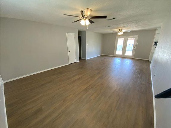Spare room with visible vents, baseboards, a ceiling fan, and dark wood-style flooring