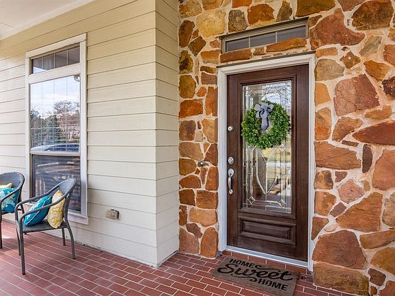 Stonework frames the door of this covered front porch with brick tile floor.