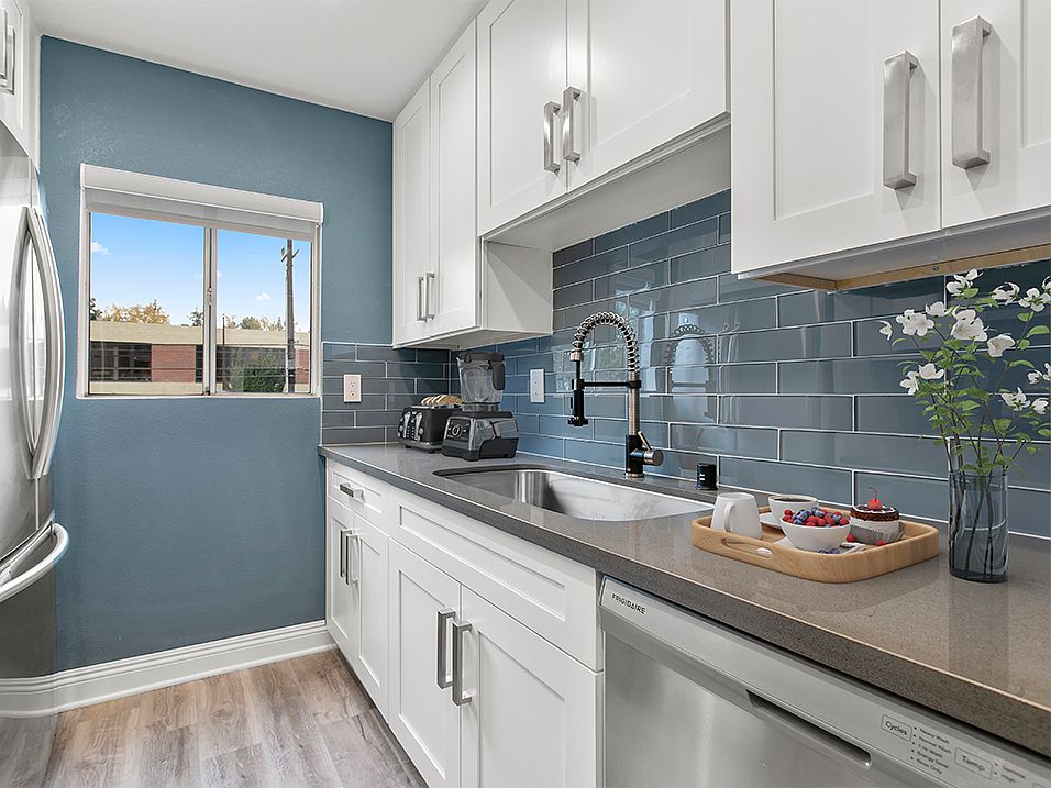 Blue tiled kitchen with stainless steel fridge and dish washer.