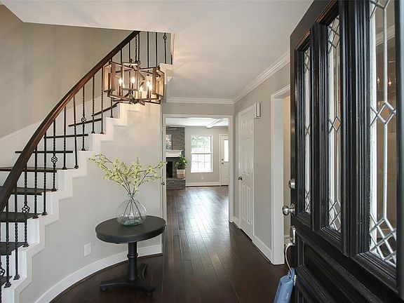 WELCOME HOME: Open the front door to new engineered hardwood flooring that has been installed throughout the living spaces downstairs. A curved staircase with wood treads and iron balusters graces the entry hall, and a chandelier provides interest.
