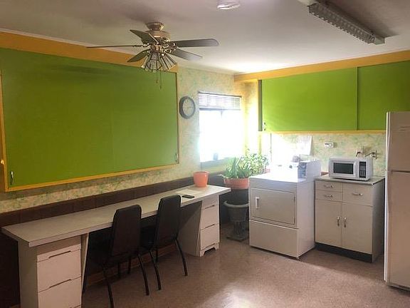 In building laundry with rinse sink and folding table (not shown large common area with large table for puzzles, sofa, coffee table, and large library of books for tenants to enjoy)