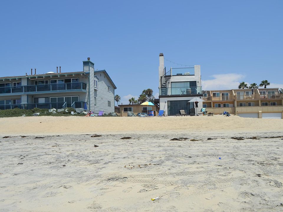 The condo building is the brown building behind the beach umbrella.