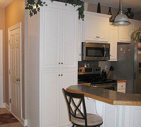 Fabulous kitchen with large pantry cabinet and stainless steel appliances. Down hall is powder room, laundry room and door (shown) to garage. Make sure to see the extra side area in the garage, which would be great for a workshop or golf cart parking!