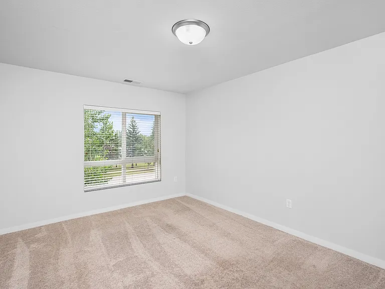 Bright and airy bedroom with plush carpeting and a large window showcasing lovely outdoor views. Bright and airy bedroom with plush carpeting and a large window showcasing lovely outdoor views.