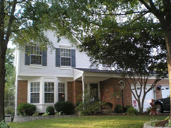 two bay windows and beautiful planters around mature trees