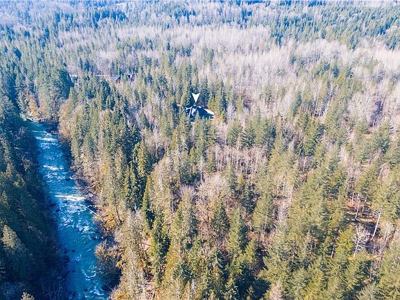 The Sultan River running through the property. See the house to the right side (white arrow). Trails lead down to the river for access to fishing for Trout, Salmon, or a swim in the summer.  Enjoy nature on this private 20 acres of natural forested land. Much of the land is on the left side of the river.