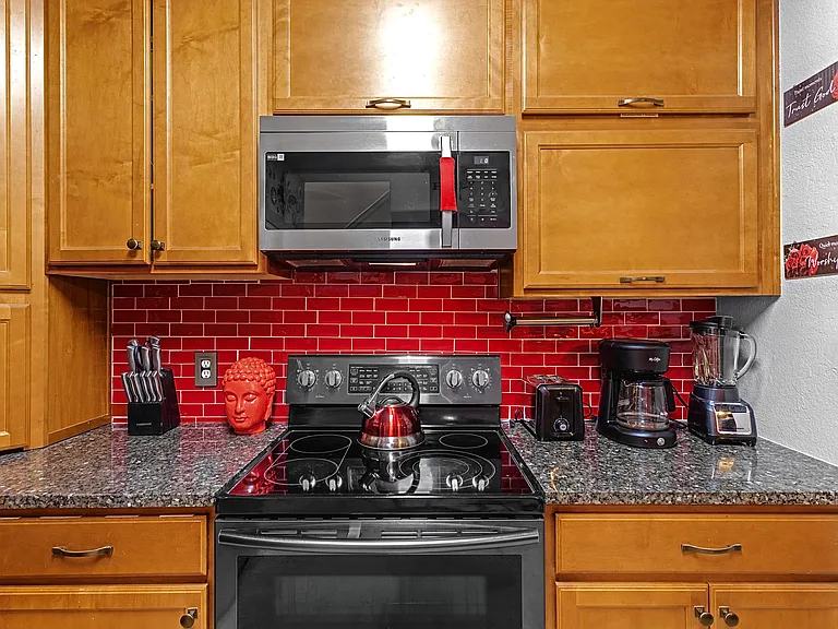 Well-equipped kitchen with modern appliances and a stylish red tile backsplash. Perfect for whipping up a delicious meal.