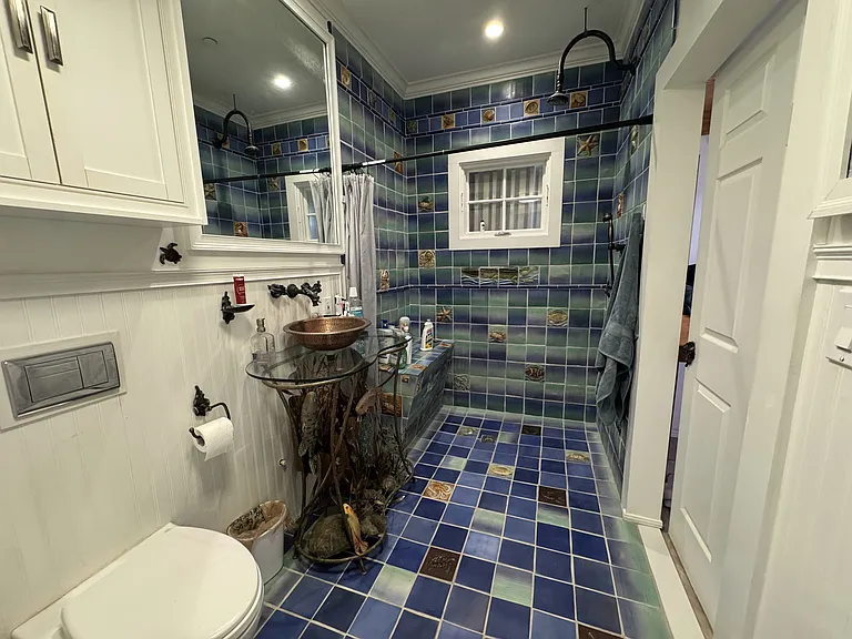 Main bathroom has been upgraded with walk-in shower and beautiful tiling throughout and unique sink art sculpture.