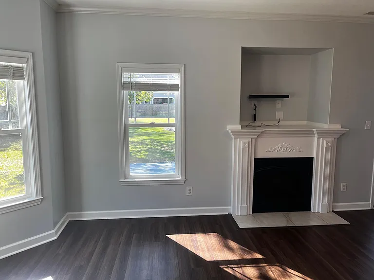 Bright living room with a decorative electric fireplace, built-in display niche, and abundant natural light.