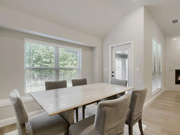 Vaulted ceiling dining area featuring a built-in fireplace, wood-finish flooring, and a glass-paneled exterior door