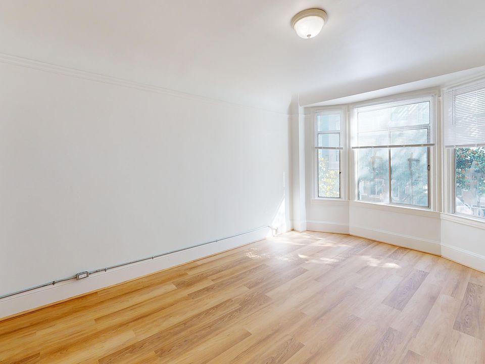 Sunlit living room with a large window and wood-like flooring