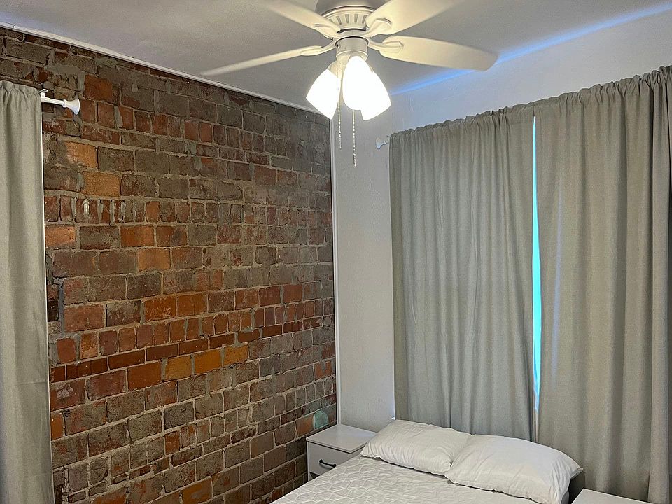 A private and cozy rear bedroom furnished with a full-sized bed, desk, chair, and dresser. Features a walk-in closet with shelving for additional storage. The soft lighting and neutral tones create a peaceful retreat.