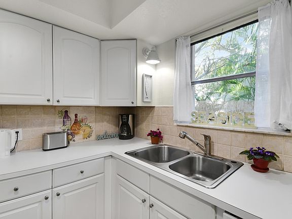 Kitchen window provides light, privacy and lovely view of your very own outdoor area. New sconce added on left side of sink for additional lighting.