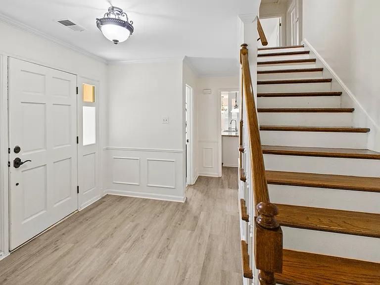 Impressive foyer with classic wainscoting and a grand staircase with rich wood bannisters _ a truly welcoming entrance.