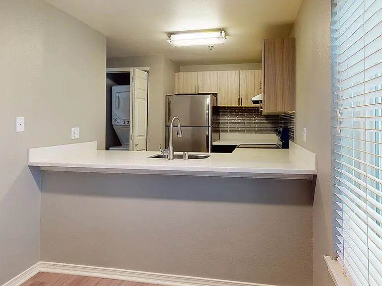 Apartment kitchen with stainless steel appliances, quartz countertops and wood-style flooring.