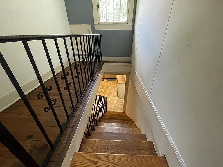 Original hardwoods and wrought iron line the staircase.