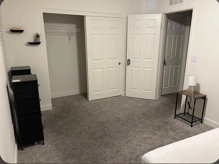 Carpeted bedroom with a spacious closet, neutral finishes, and room for a bed plus a nightstand or dresser.