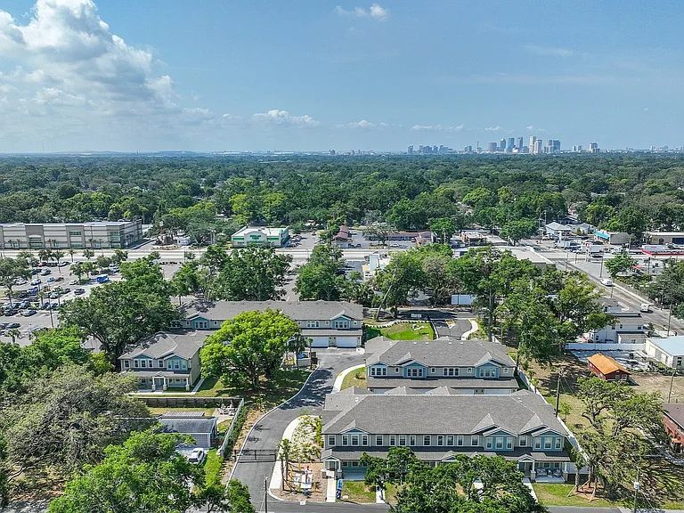 Scenic aerial view of a modern apartment complex surrounded by lush greenery, offering serene living with easy city access.