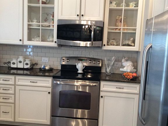 Kitchen with glass cabinets, granite countertops and subway tile backsplash.