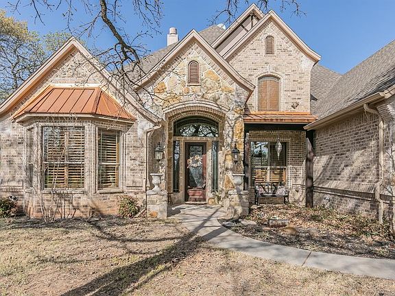 View of front of house with stone siding, brick siding, and a chimney