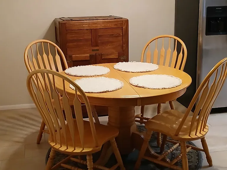 The dining area features an expandable round table. In the background is a refurbished antique ice box that can be used for storage.