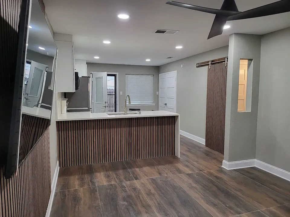 Open-concept living area with wood-finish flooring, recessed lighting, and a modern ceiling fan