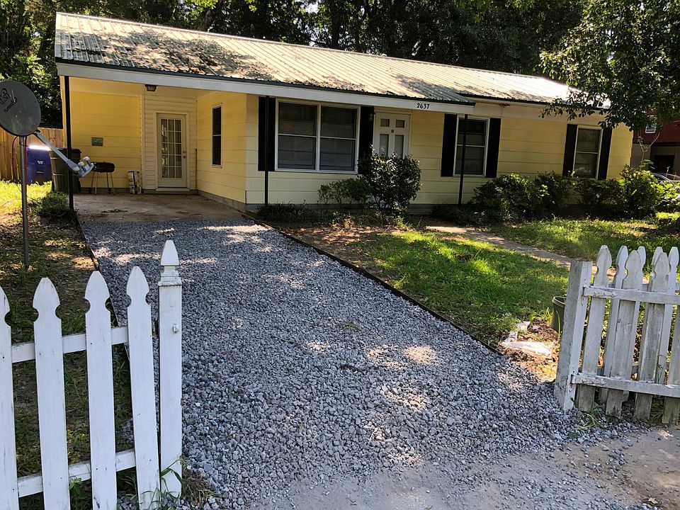 Front of the home with gravel driveway.